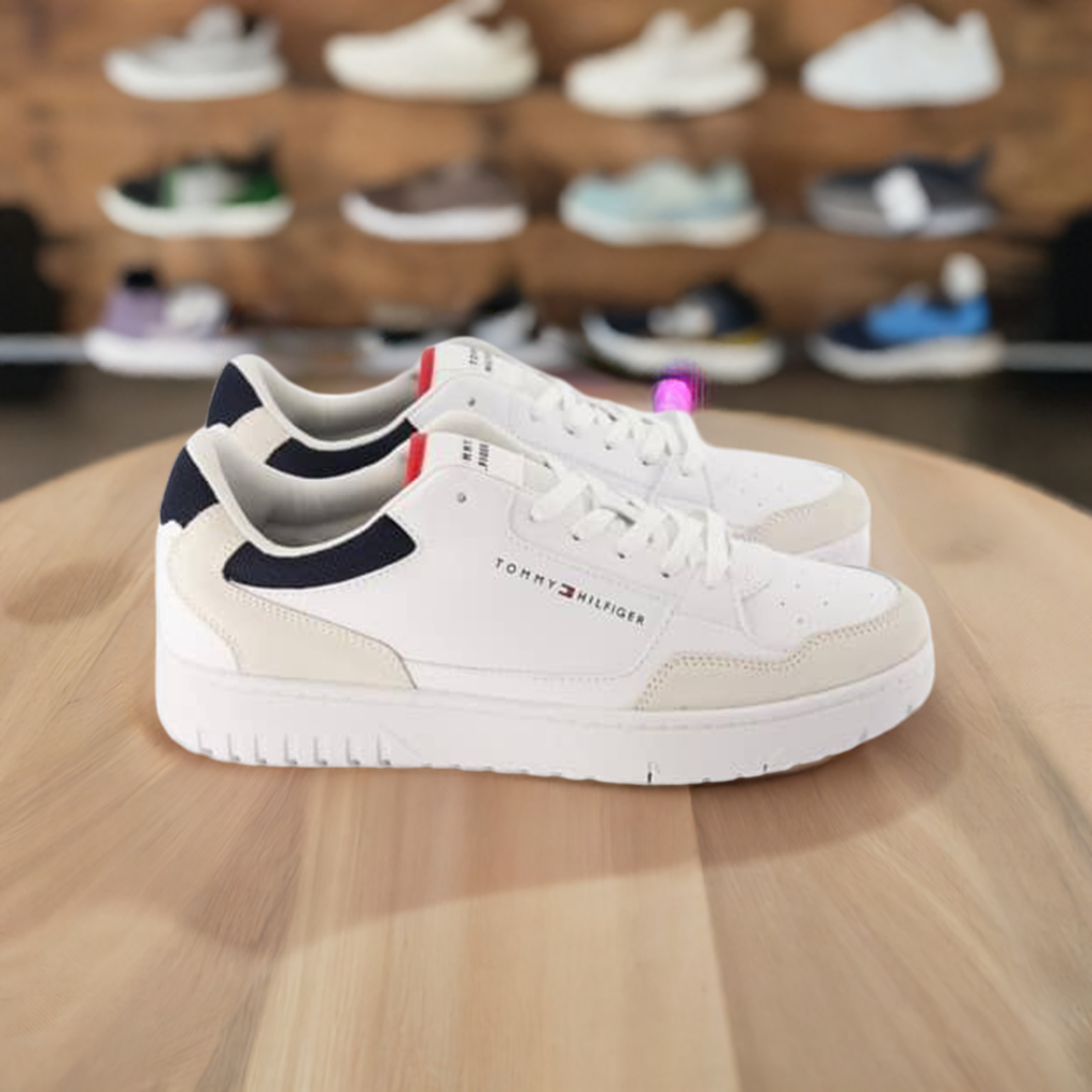 Side View of white Tommy Hilfiger Sneakers with lace -up design and navy blue accents on the sides and back, featuring red detail